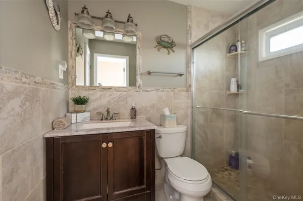 a bathroom with a granite countertop toilet sink vanity and mirror