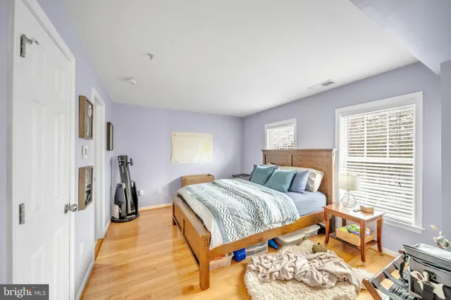 a bed sitting in a bedroom next to a window and a wooden floor