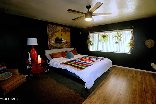 a bedroom with a bed and lamp on desk with wooden floor