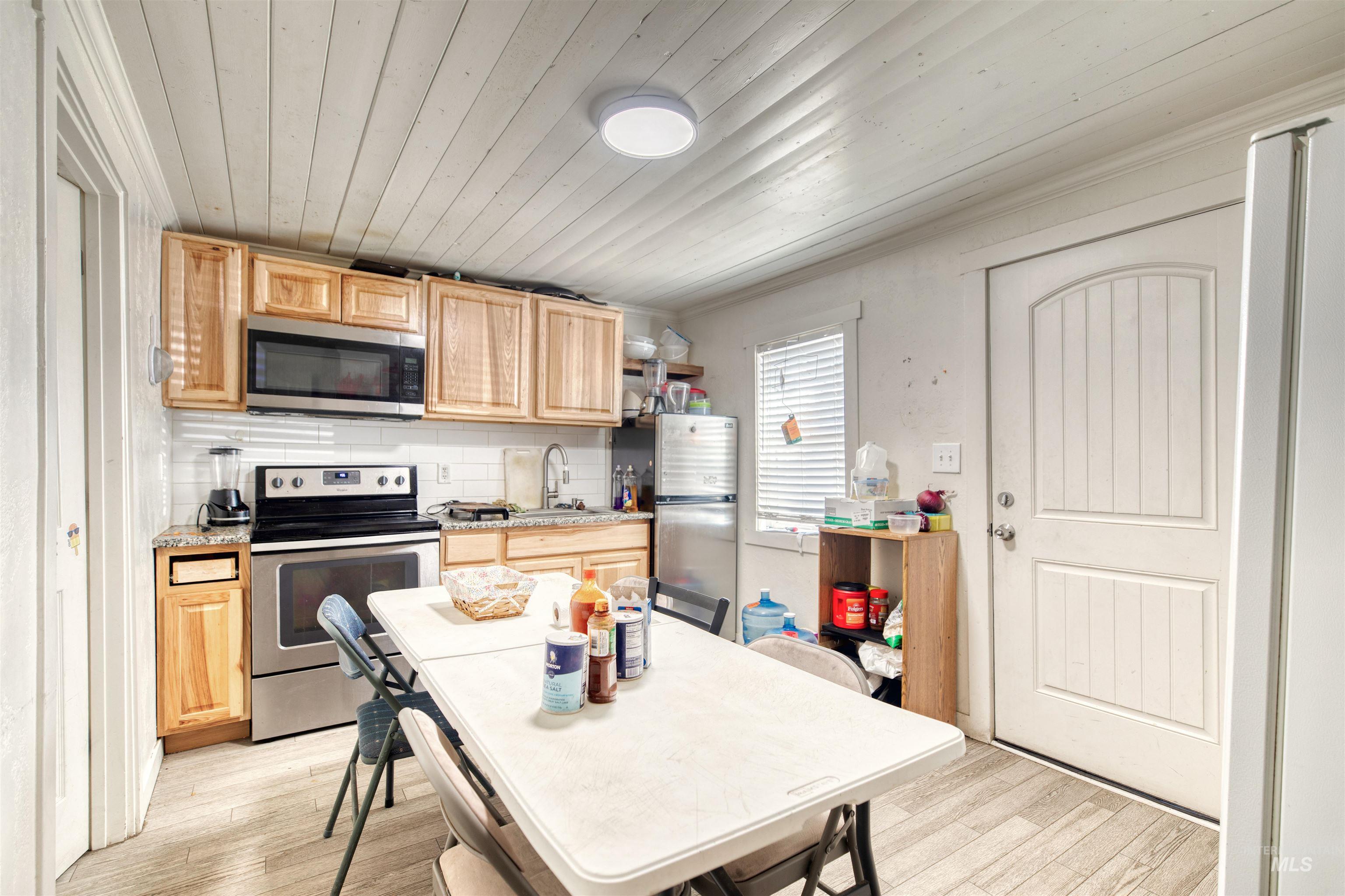 110 East Main Street Nyssa, OR 97913 - Photo 12 of 17 Kitchen with stainless steel appliances, light brown cabinets, light wood-type flooring, backsplash, and wood ceiling