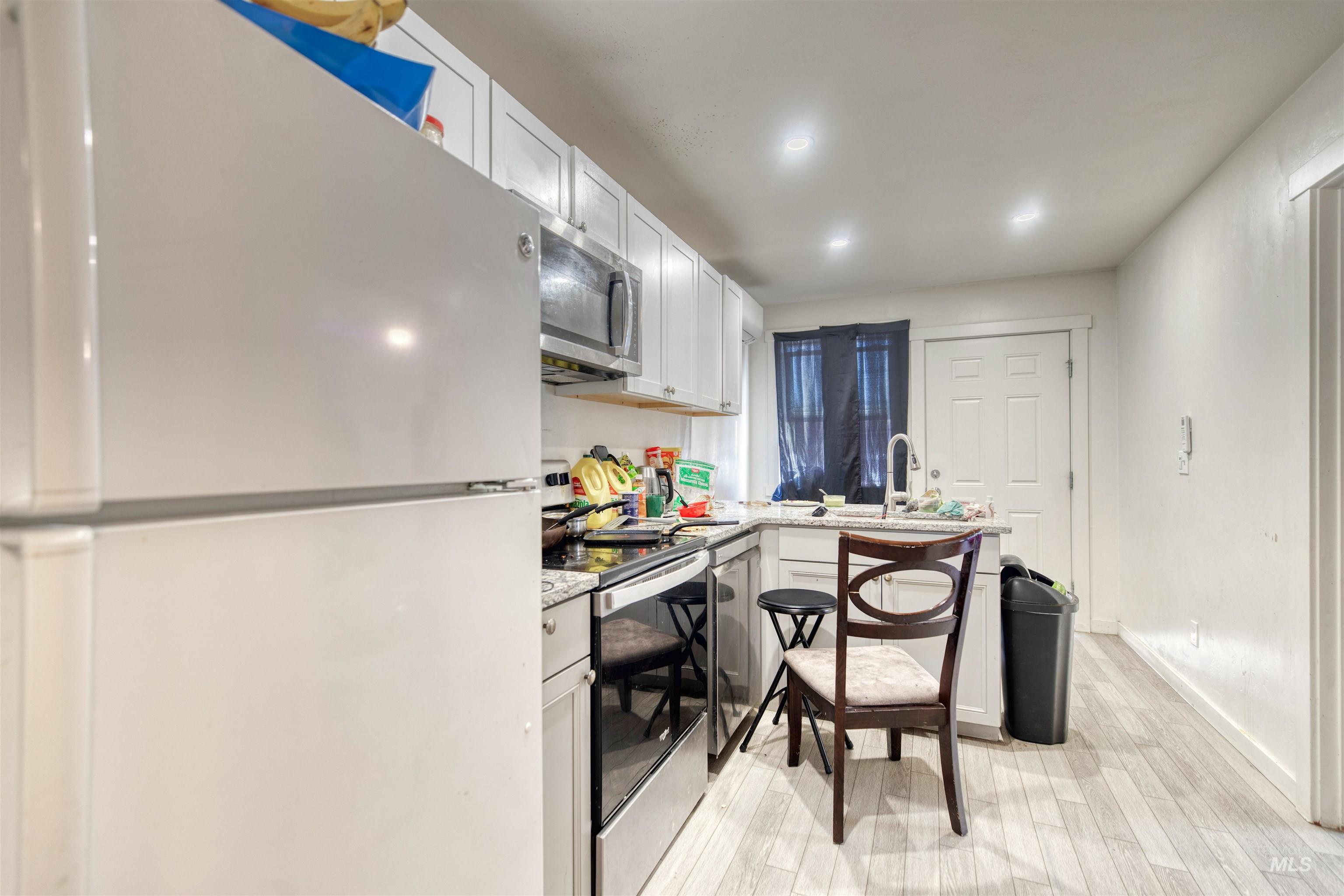 110 East Main Street Nyssa, OR 97913 - Photo 5 of 17 Kitchen featuring stainless steel appliances, light wood finished floors, white cabinets, a peninsula, and light stone countertops