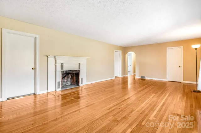 a view of empty room with wooden floor and fireplace