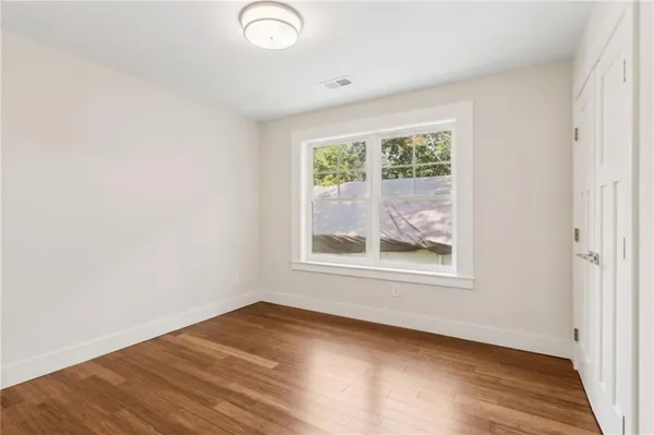 an empty room with wooden floor and windows