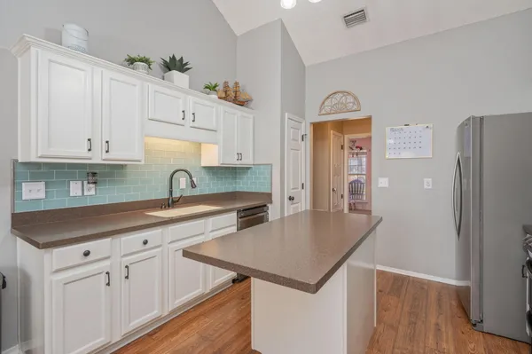 a kitchen with stainless steel appliances a stove a refrigerator a sink a stove and white cabinets