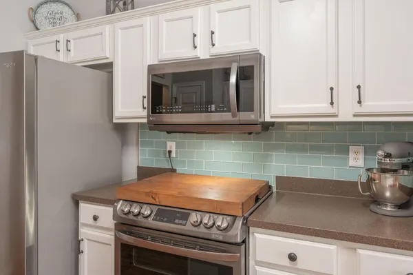 a large kitchen with granite countertop a stove top oven a sink dishwasher a dining table and chairs with wooden floor