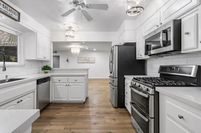 a open kitchen with granite countertop a stove a sink dishwasher and a refrigerator with wooden floor