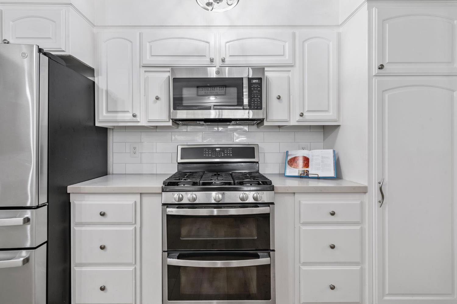 2433 Broadridge Way Stockton, CA 95209 - Photo 29 of 67 a kitchen with stainless steel appliances granite countertop white cabinets and a stove a oven with white countertops