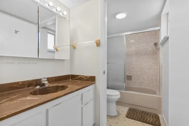 a bathroom with a granite countertop sink a toilet a mirror and shower