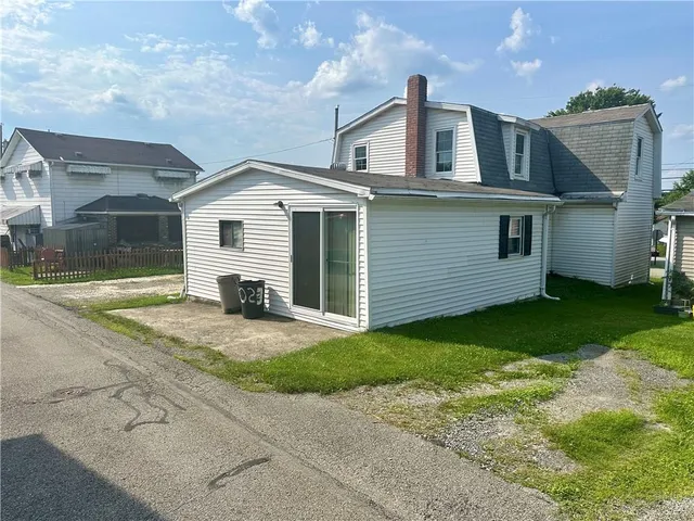 a view of a house next to a big yard with large trees