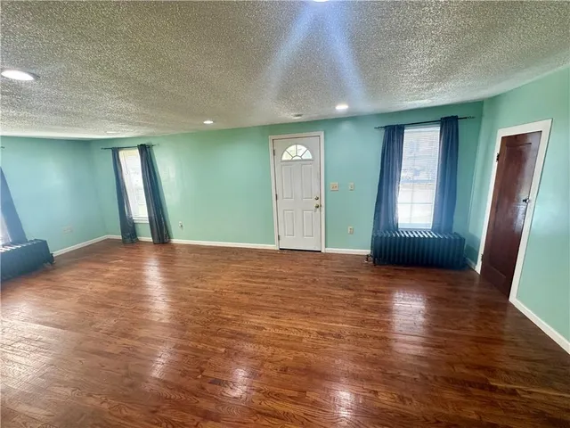 a view of an empty room with window and wooden floor