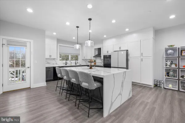 a kitchen with stainless steel appliances kitchen island granite countertop a table chairs and a refrigerator