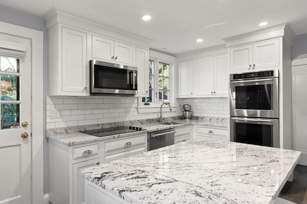 63 Oak Ridge Road Medford, MA 02155 - Photo 21 of 40 a kitchen with kitchen island granite countertop a stove top oven microwave and refrigerator