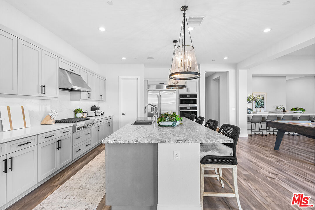 80464 Old Rnch Trail North La Quinta, CA 92253 - Photo 16 of 42 a kitchen with stainless steel appliances kitchen island granite countertop a sink a stove a dining table and chairs with wooden floor