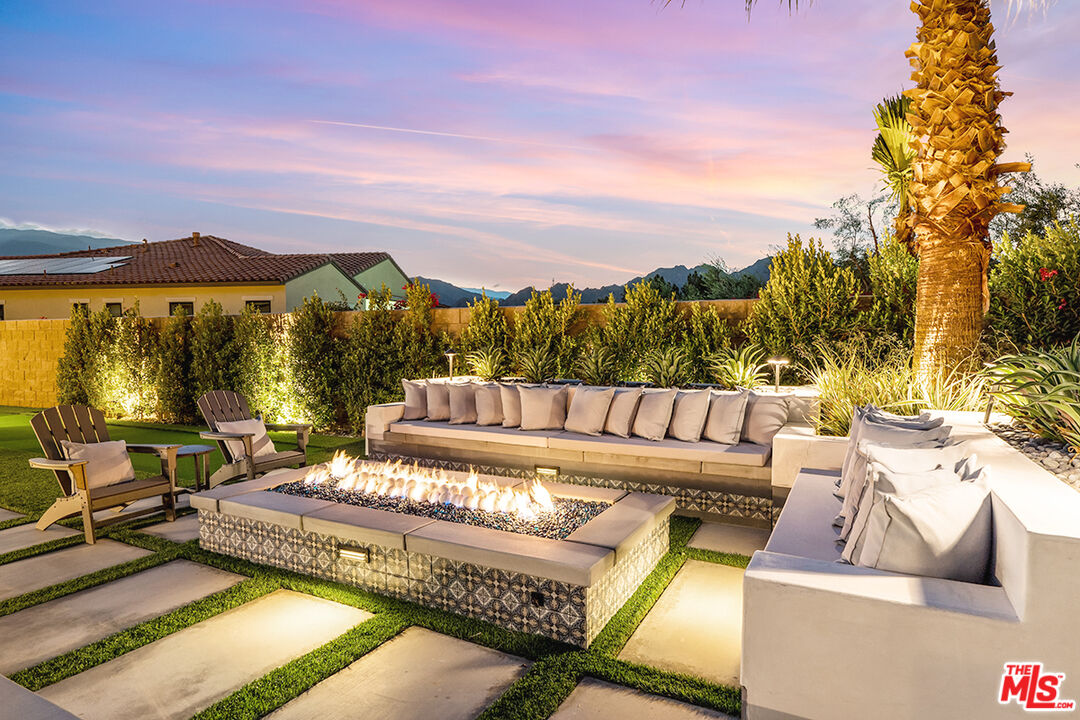 80464 Old Rnch Trail North La Quinta, CA 92253 - Photo 4 of 42 a view of a patio with couches table and chairs under an umbrella with large trees