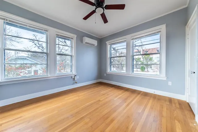 a view of an empty room with a window and wooden floor