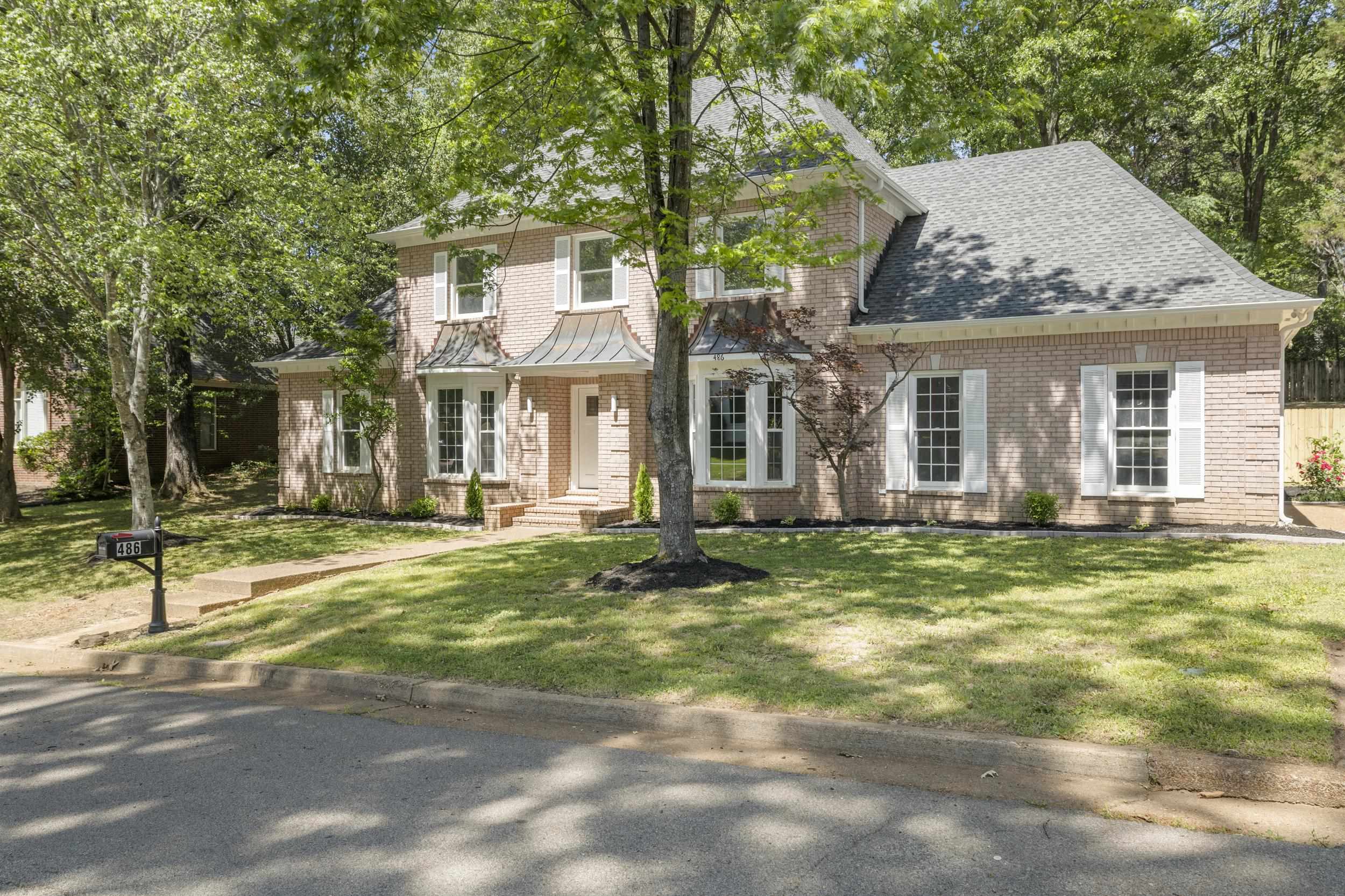 View of front of property with brick siding, a front yard, and a shingled roof