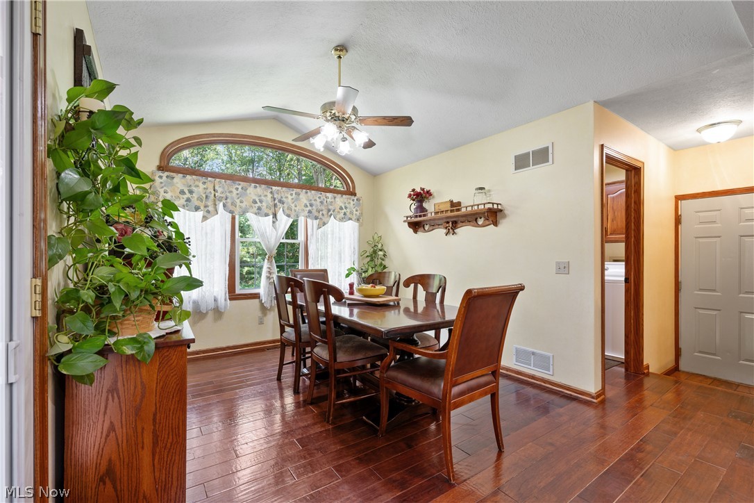 10400 Stoneacre Road Northwest Canal Fulton, OH 44614 - Photo 11 of 44 Dining space featuring dark wood-style flooring, vaulted ceiling, ceiling fan, and a textured ceiling
