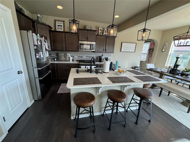 a kitchen that has a kitchen island a stove a table and chairs in it
