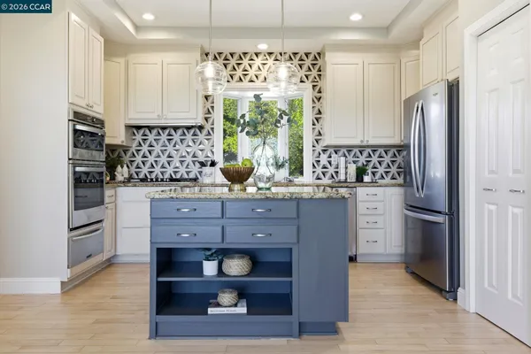 a kitchen with stainless steel appliances kitchen island granite countertop a refrigerator and a stove top oven