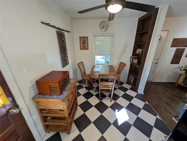 a living room with a black white checkered floor with a gaming machine and dining table
