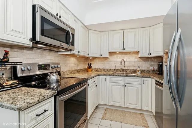 a kitchen with granite countertop white cabinets stainless steel appliances and a counter space