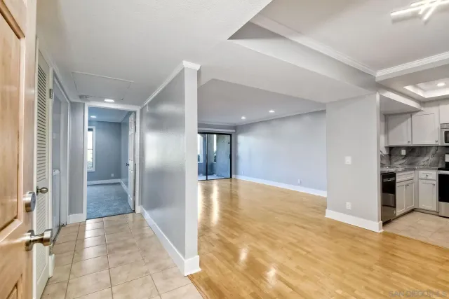 a view of a hallway with stainless steel appliances kitchen island granite countertop a refrigerator and a sink