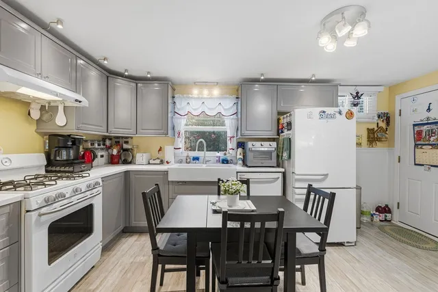 a kitchen with refrigerator a stove a dining table and chairs