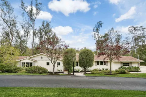 a front view of a house with a garden and trees