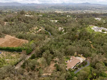 an aerial view of residential houses with outdoor space and trees