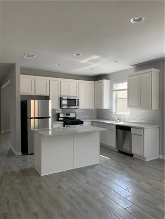 a kitchen with stainless steel appliances granite countertop a refrigerator and a stove top oven