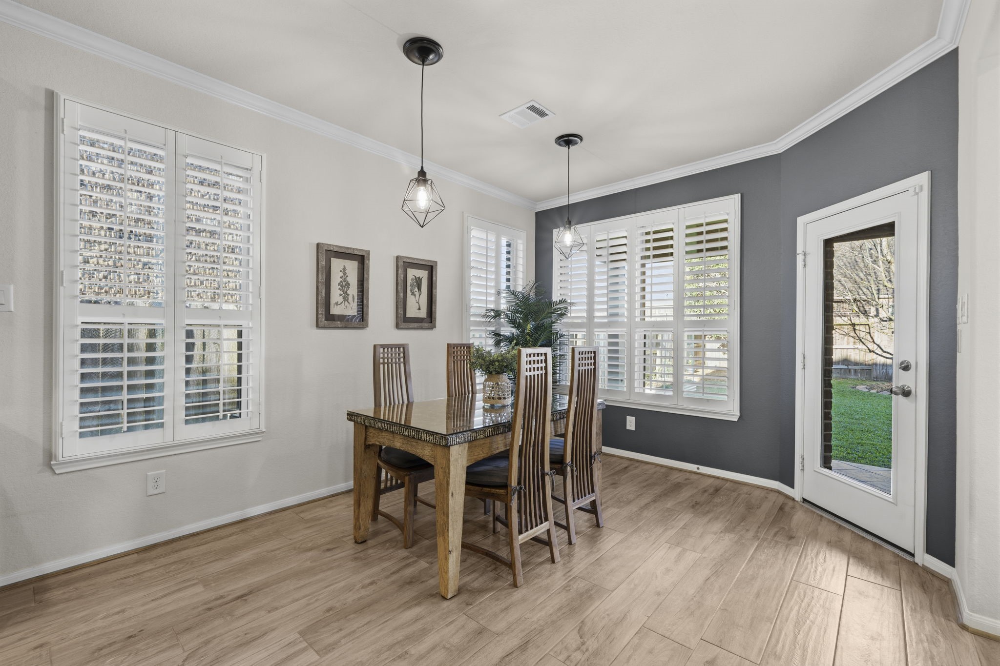 16731 Doubletree Ranch Drive Cypress, TX 77433 - Photo 13 of 44 Bright dining area with large windows with plantation shutters and modern light fixtures. Features a glass door leading to a backyard, creating a seamless indoor-outdoor flow.