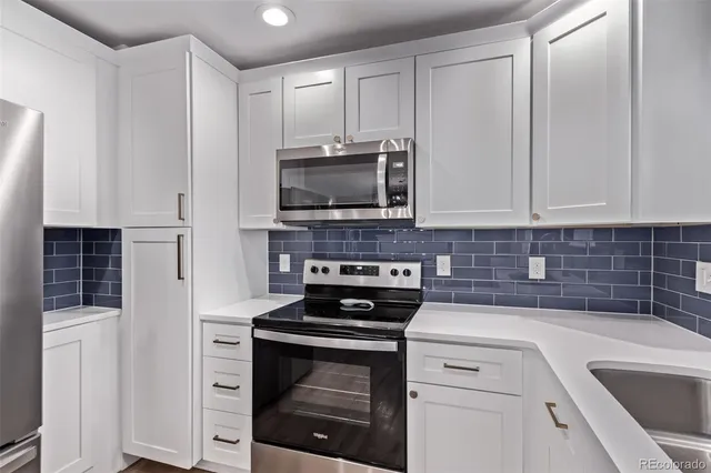 a kitchen with white cabinets and black appliances