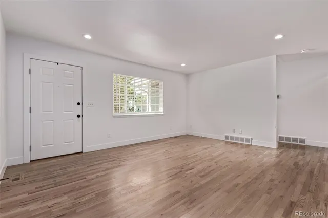 an empty room with wooden floor and window