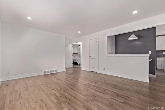 a view of an empty room with wooden floor and closet