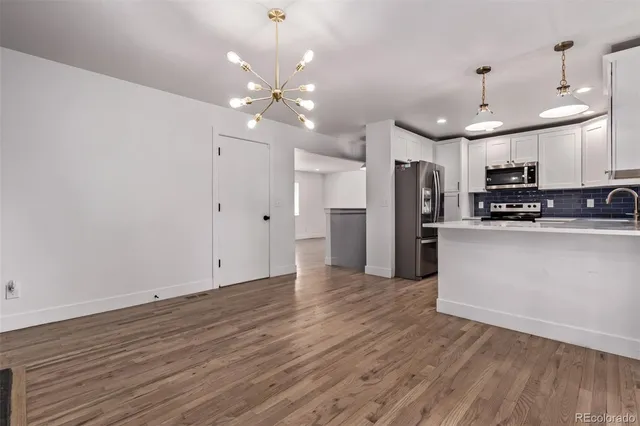 a view of a kitchen with a refrigerator a ceiling fan and wooden floor