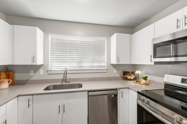 6231 Winding Way, Unit K105 Hurricane, UT 84737 - Photo 10 of 20 Kitchen with stainless steel appliances, white cabinets, light stone counters, and a textured ceiling