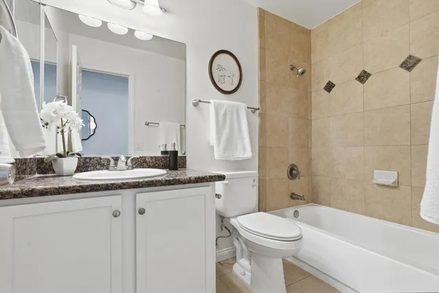a bathroom with a granite countertop sink mirror toilet and a bathtub