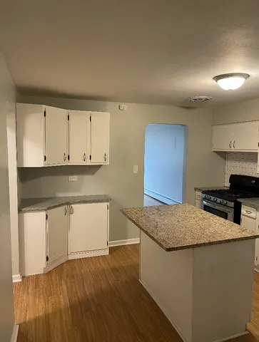 a kitchen with granite countertop a sink a stove and cabinets