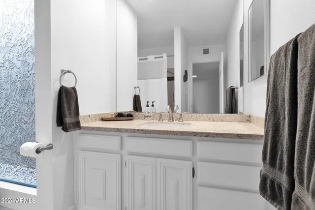 a bathroom with a granite countertop sink and a mirror