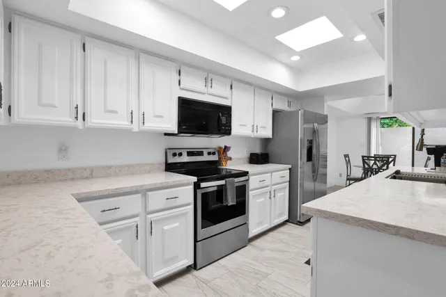 a kitchen with white cabinets and stainless steel appliances