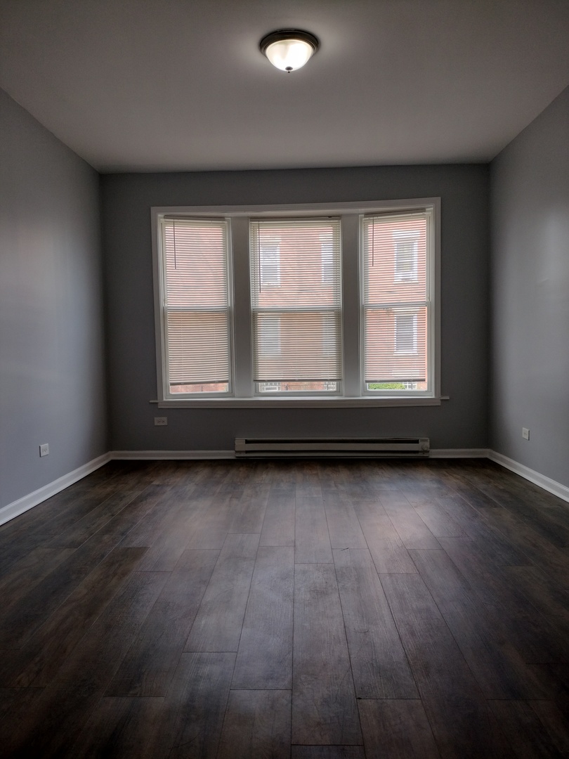 6601 South Green Street, Unit 8211 Chicago, IL 60621 - Photo 2 of 12 an empty room with wooden floor and windows