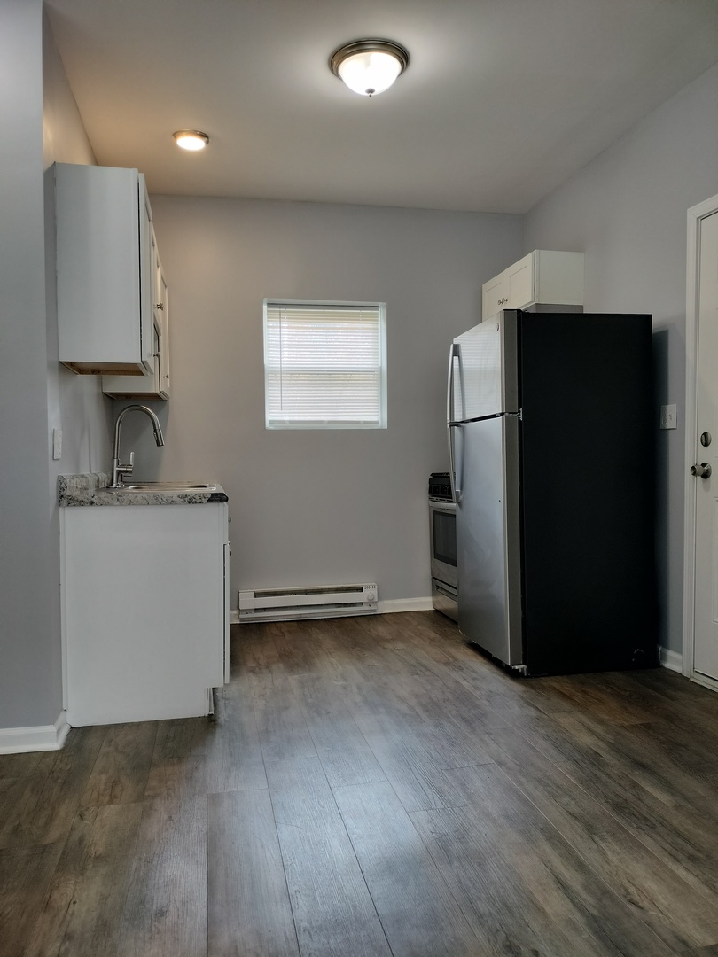 6601 South Green Street, Unit 8211 Chicago, IL 60621 - Photo 3 of 12 a view of a refrigerator in kitchen and an empty room with wooden floor
