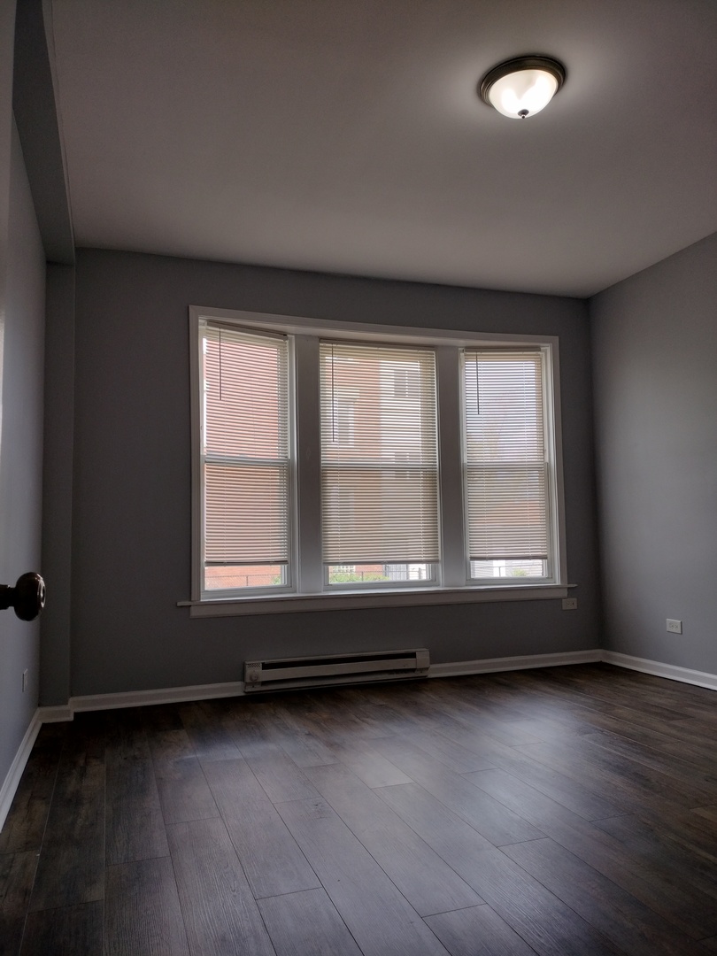 6601 South Green Street, Unit 8211 Chicago, IL 60621 - Photo 6 of 12 an empty room with wooden floor and windows