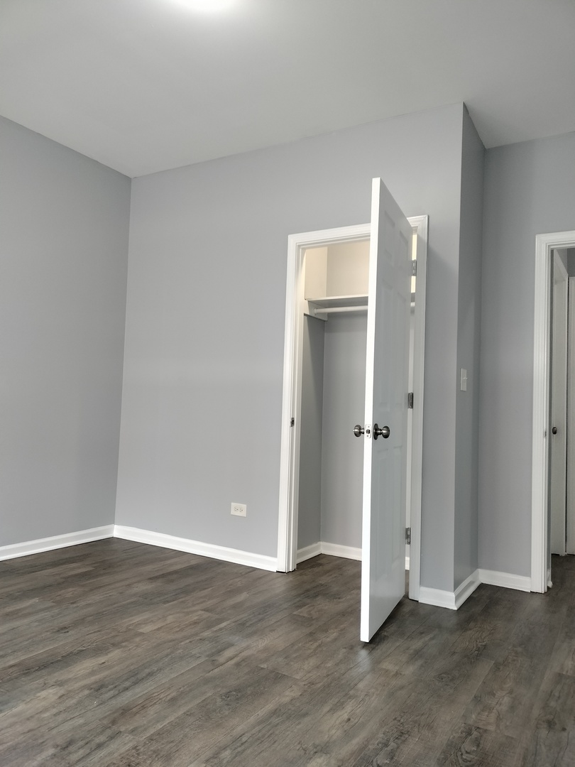 6601 South Green Street, Unit 8211 Chicago, IL 60621 - Photo 8 of 12 an empty room with wooden floor and window