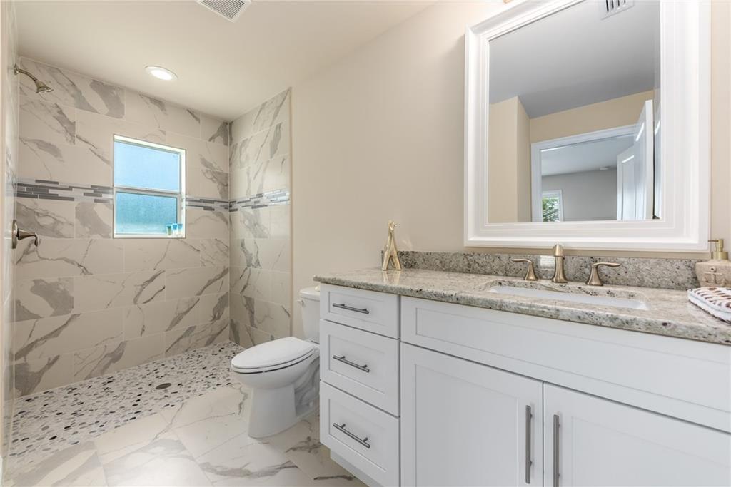 4833 Southeast Pilot Way Stuart, FL 34997 - Photo 33 of 37 a bathroom with a granite countertop sink a toilet and a mirror
