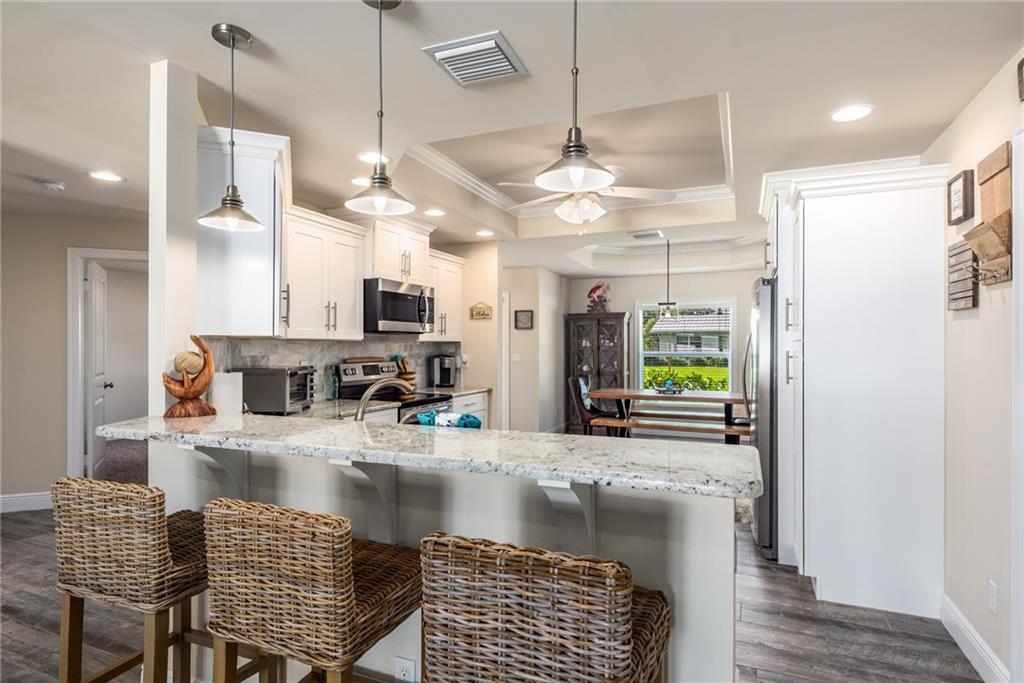 4833 Southeast Pilot Way Stuart, FL 34997 - Photo 7 of 37 a kitchen with kitchen island granite countertop a refrigerator a stove and a sink with wooden floor