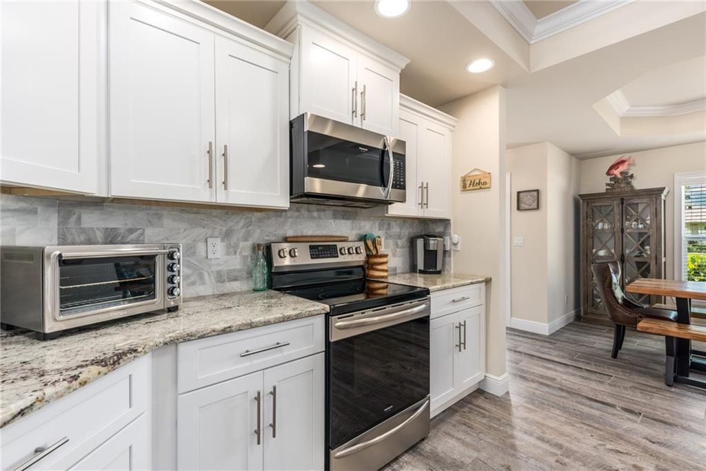 4833 Southeast Pilot Way Stuart, FL 34997 - Photo 10 of 37 a kitchen with stainless steel appliances granite countertop a stove microwave and cabinets
