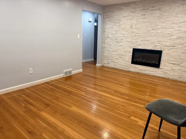 a view of empty room with wooden floor and fireplace