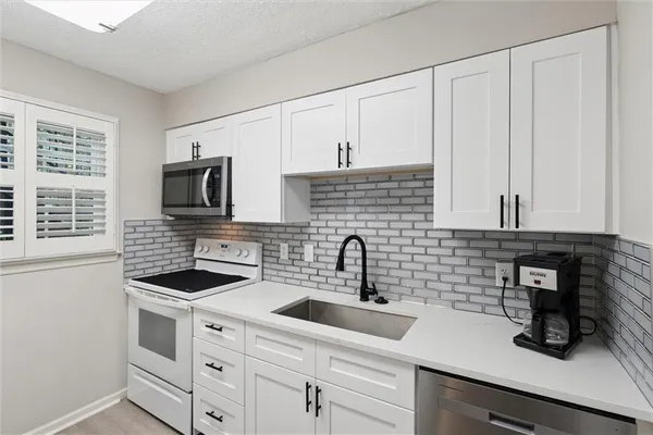 a kitchen with white cabinets a sink and a stove with wooden floor
