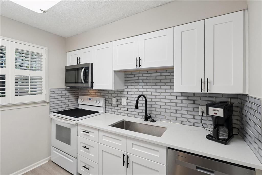 6700 Roswell Road, Unit 31B Atlanta, GA 30328 - Photo 2 of 32 a kitchen with white cabinets a sink and a stove with wooden floor